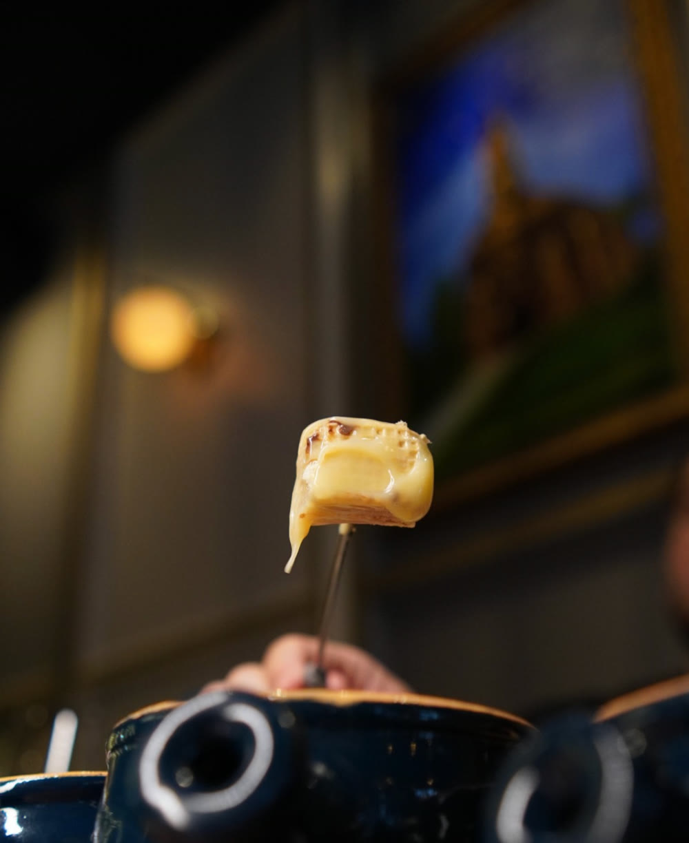 Fondue de queijo suíço puxando no garfo, à mesa do St. Gallen Lummi